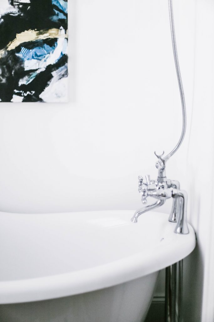 Guest Bathroom Reveal Modern Historic Downtown Charleston Home Renovation   // Charleston Fashion Blogger Dannon Like The Yogurt    Urban Outfitters black hexagon hand towel ring DIY cedar and moss brass sconce white clawfoot tub shower round brass vanity mirror target cement planter hex white vase white walls marble cararra countertops black and white geometric kilum rug nate burkus