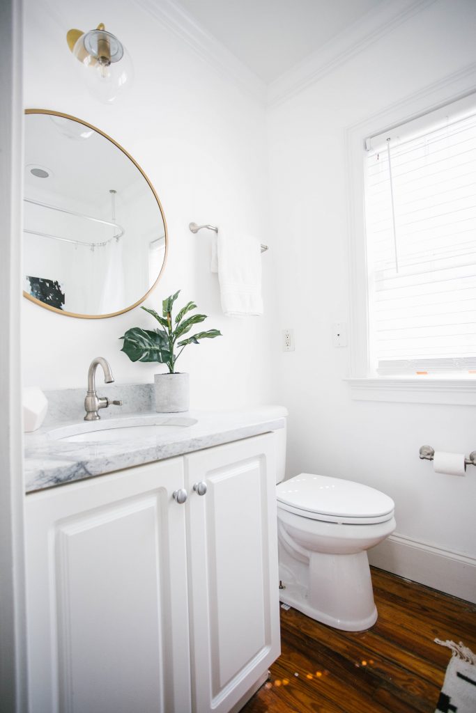 Guest Bathroom Reveal Modern Historic Downtown Charleston Home Renovation   // Charleston Fashion Blogger Dannon Like The Yogurt    Urban Outfitters black hexagon hand towel ring DIY cedar and moss brass sconce white clawfoot tub shower round brass vanity mirror target cement planter hex white vase white walls marble cararra countertops black and white geometric kilum rug nate burkus