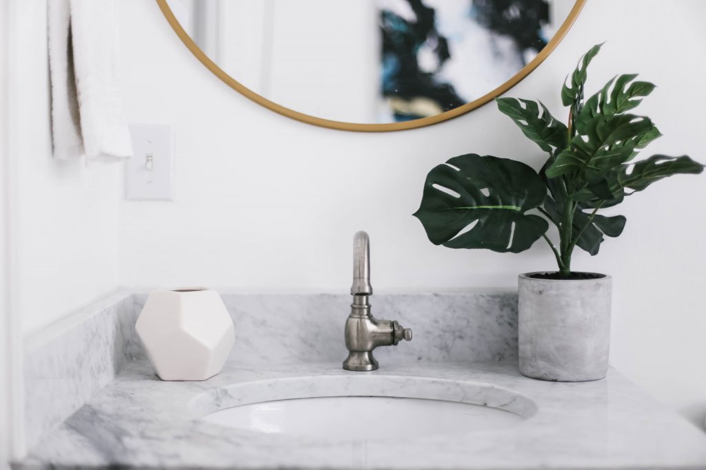 Guest Bathroom Reveal Modern Historic Downtown Charleston Home Renovation   // Charleston Fashion Blogger Dannon Like The Yogurt    Urban Outfitters black hexagon hand towel ring DIY cedar and moss brass sconce white clawfoot tub shower round brass vanity mirror target cement planter hex white vase white walls marble cararra countertops black and white geometric kilum rug nate burkus